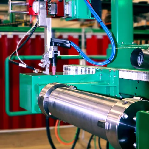Machines Una máquina de soldadura automatizada de color verde trabaja con precisión sobre un componente metálico cilíndrico pulido en una fábrica.